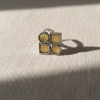 Silver ring with yellow gemstones on a textured beige surface