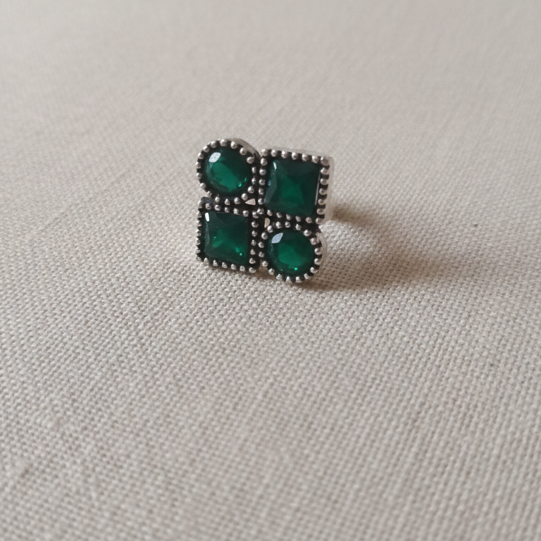 Toe Ring with green gemstones on a light gray fabric background
