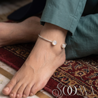 Model wearing sleek silver open cuff ankle kada featuring teardrop gemstone ends
