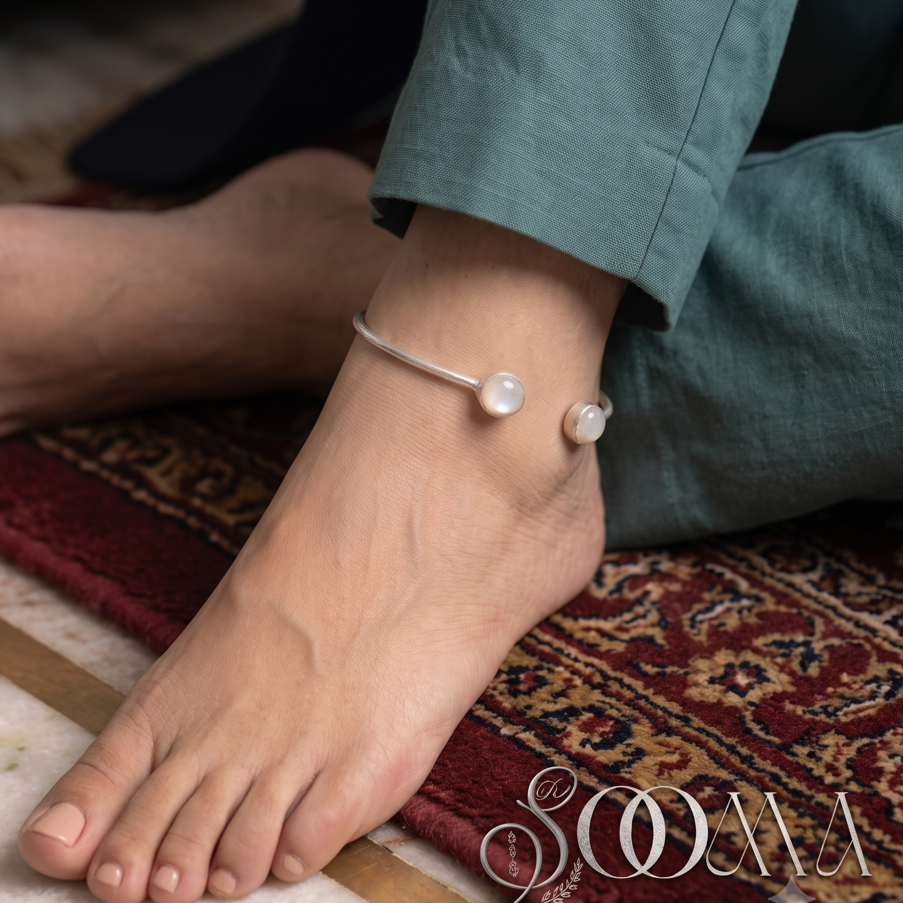 Model wearing sleek silver open cuff ankle kada featuring teardrop gemstone ends