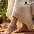 Close-up view of woman foot on stone step adorned with an oxidized silver crescent moon and flower ghungroo layered anklet stack
