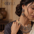 Model wearing handcrafted oxidized silver tribal bib necklace with ruby stone medallions and matching jhumka earring