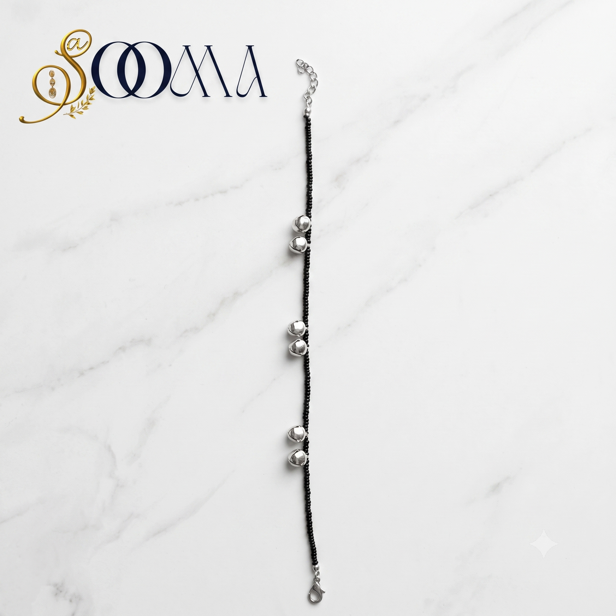 Sooma brand black seed bead anklet with silver ghungroo clusters displayed flat on white marble