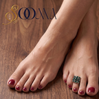 Close-up view of woman's foot adorned with a square black onyx floral cluster toe ring on polished wood