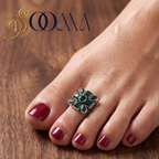 Front view of model feet with deep red polish wearing an oxidized silver geometric green onyx toe ring on wooden background