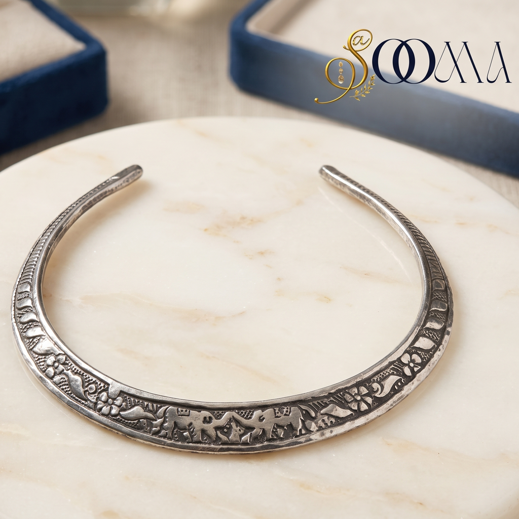 Sooma brand oxidized silver carved elephant Hasli necklace displayed flat on round white marble slab