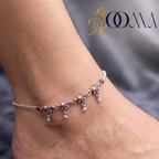 Close-up shot of woman's ankle wearing oxidized silver elephant charm payal with ruby-pink beads and dangling drops