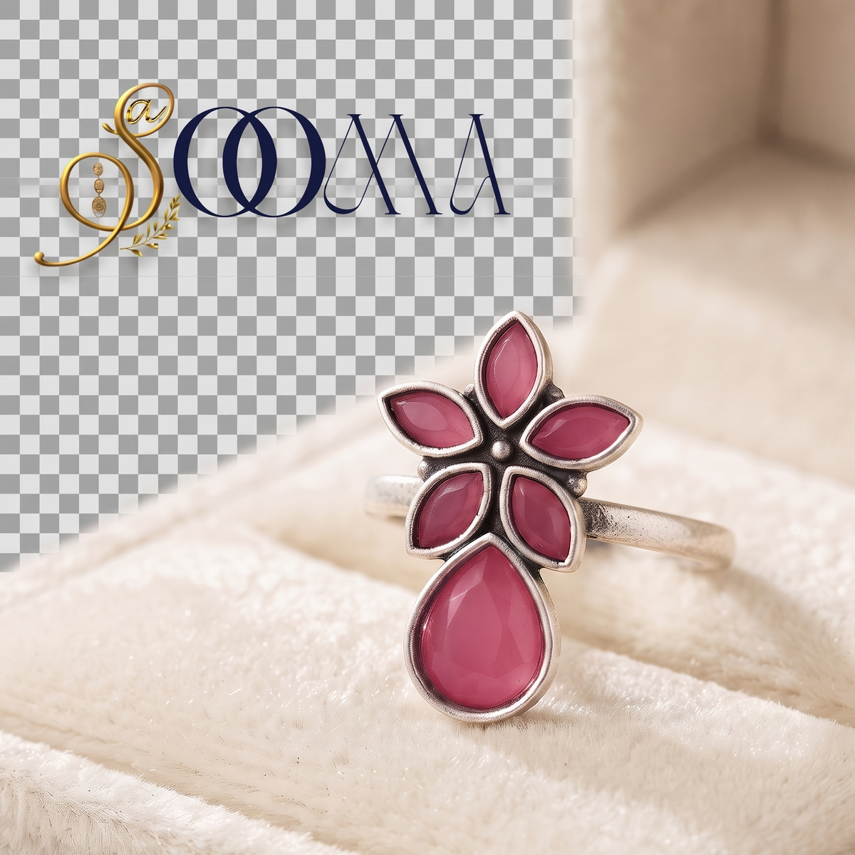 A silver ring with a flower-shaped setting and a teardrop-shaped pink stone, displayed inside a cream-colored jewelry box. A logo watermark for 'S.