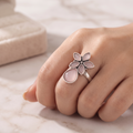 Side profile view of model hand styling an oxidized silver pink quartz teardrop flower statement ring