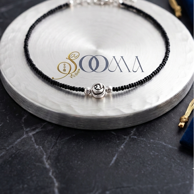 Sooma brand black seed bead anklet with center oxidized silver rose motif displayed on silver plate