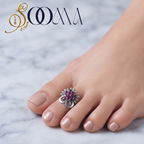 Front view of model feet with nude nail polish wearing an oxidized silver royal gulabi stone sunburst toe ring on marble floor