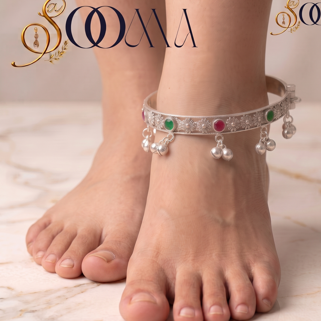 Close-up of woman's ankle showcasing hinged oxidized silver payal kada with green and ruby cabochon stones