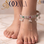 Close-up of woman's ankle showcasing hinged oxidized silver payal kada with green and ruby cabochon stones