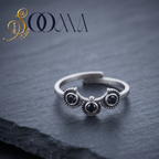 A silver-toned open ring with three circular black stone settings, displayed on a dark slate surface with the SOOMA brand logo in the upper left corner.