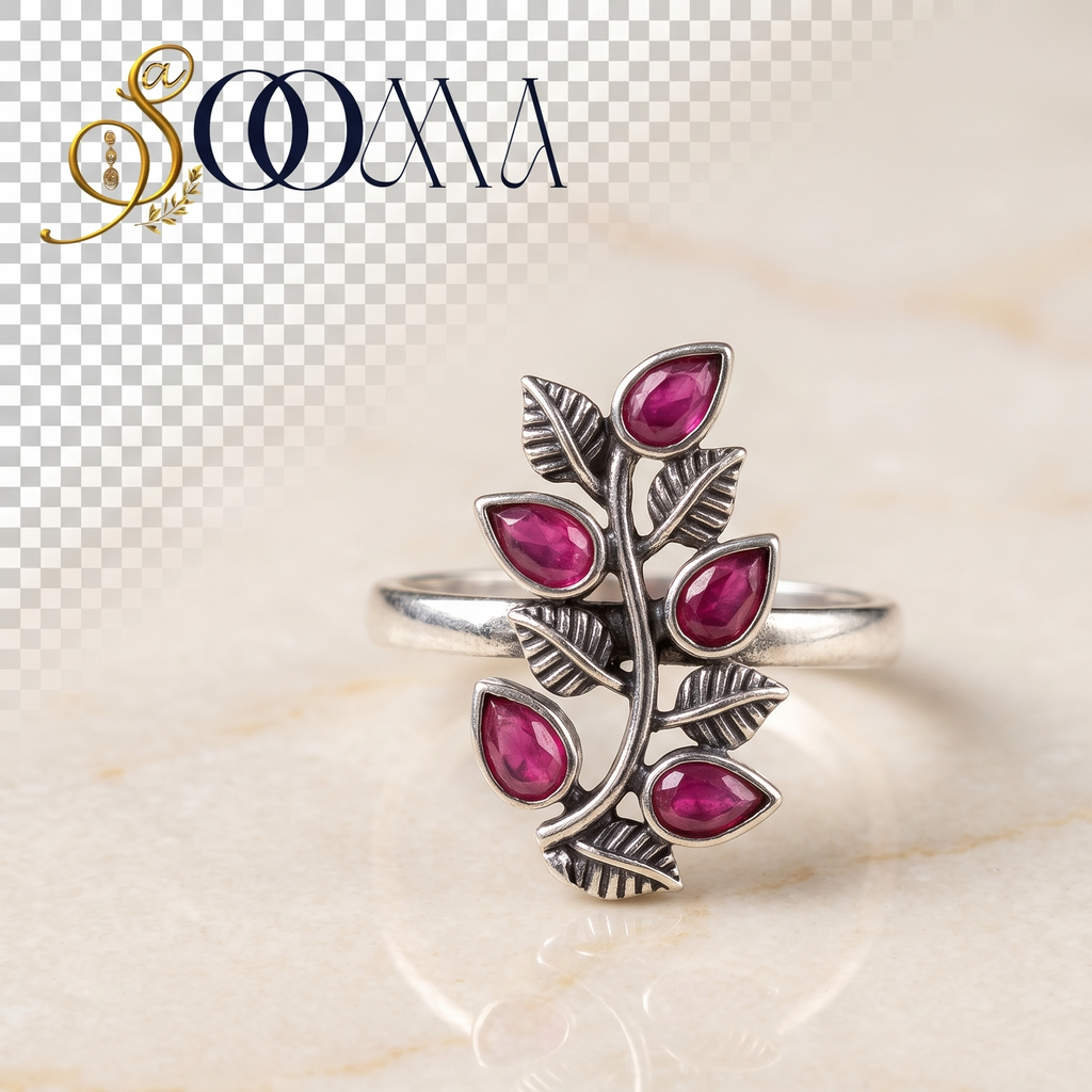 Sooma brand handcrafted oxidized silver toe ring featuring a vertical leafy vine set with teardrop ruby red stones on marble backdrop