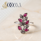 Sooma brand handcrafted oxidized silver toe ring featuring a vertical leafy vine set with teardrop ruby red stones on marble backdrop
