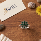Sooma brand handcrafted oxidized silver green onyx 8-petal floral toe ring displayed flat on wooden surface with decorative stones