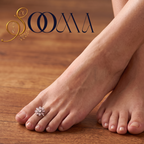 Close-up view of woman foot adorned with an 8-petal green onyx floral cluster toe ring on velvet cushion