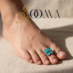 Foot wearing a turquoise toe ring with 'Sooma' branding.