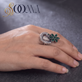 Side view of model hand styling an oxidized silver peacock statement ring with a green onyx flower crown on dark slate surface
