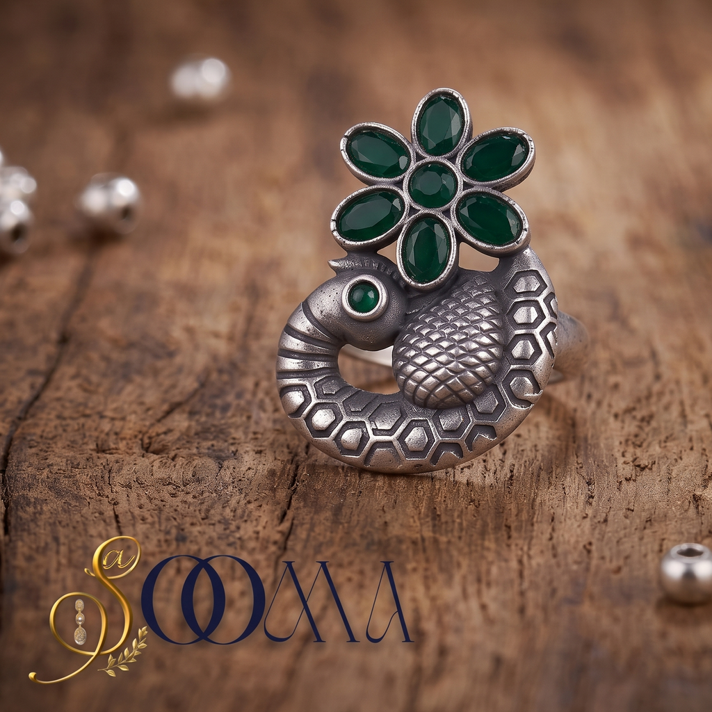 Sooma brand handcrafted oxidized silver carved peacock ring featuring green onyx flower centerpiece displayed flat on rustic wood