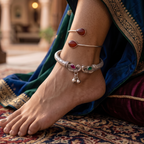 Side perspective view of model wearing royal oxidized silver peacock kada and carnelian bypass ankle cuff stack paired with silk saree