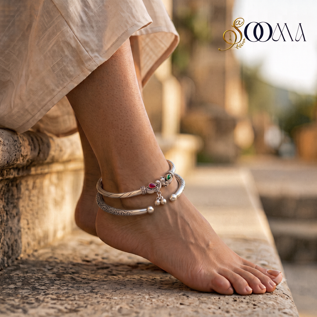 Close-up view of model foot adorned with a royal oxidized silver peacock head ghungroo kada and carved floral vine cuff stack