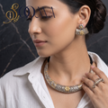 Model in white linen shirt wearing dual-tone oxidized silver and gold carved Hasli necklace set with matching earrings