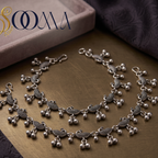 Sooma brand pair of oxidized silver peacock link payal anklets with ghungroo bells displayed flat on a brass tray