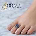 Front view of model feet with nude nail polish wearing an oxidized silver royal blue stone sunburst toe ring on marble floor