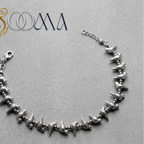 Sooma brand handcrafted oxidized silver bird charm anklet with lobster clasp displayed flat on grey surface