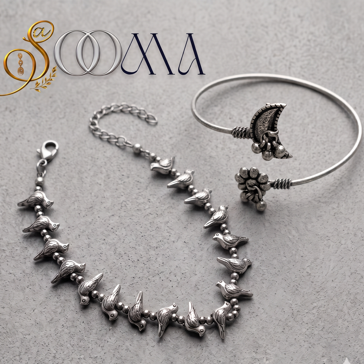 Sooma brand flat lay view of 2-piece silver ankle stack featuring bird charm chain anklet and crescent moon flower ghungroo bypass cuff on grey stone