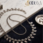 Sooma brand oxidized silver leaf and cowrie shell waist chain displayed flat on marble and dark blue velvet background