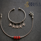 Sooma brand flat lay view of 2-piece ankle stack featuring carved leaf charm cuff and red carnelian bead snake chain on dark stone surface