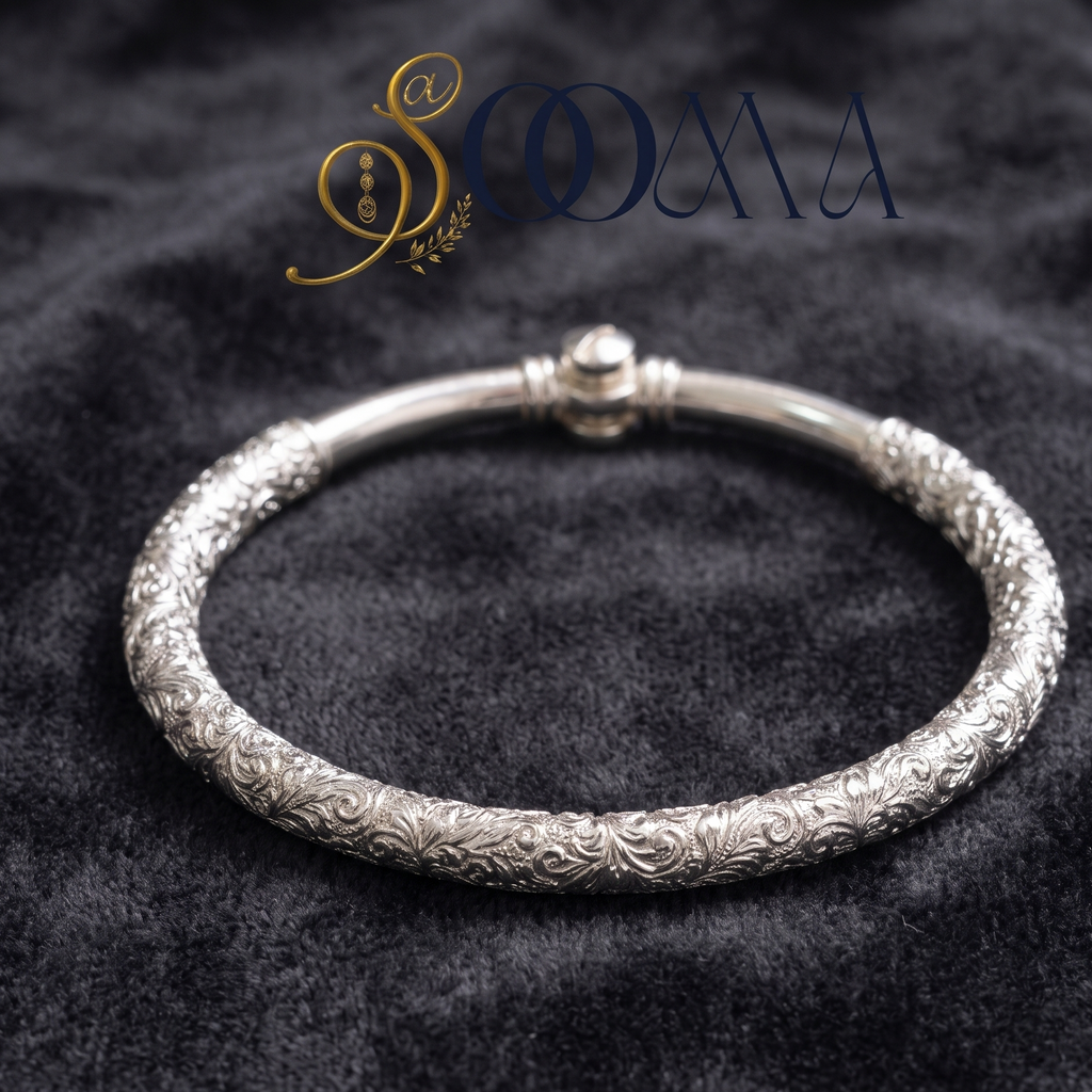 An ornate silver bangle bracelet with intricate floral engraving, displayed on a dark textured velvet background with the brand name 'SOOMA' at the top.