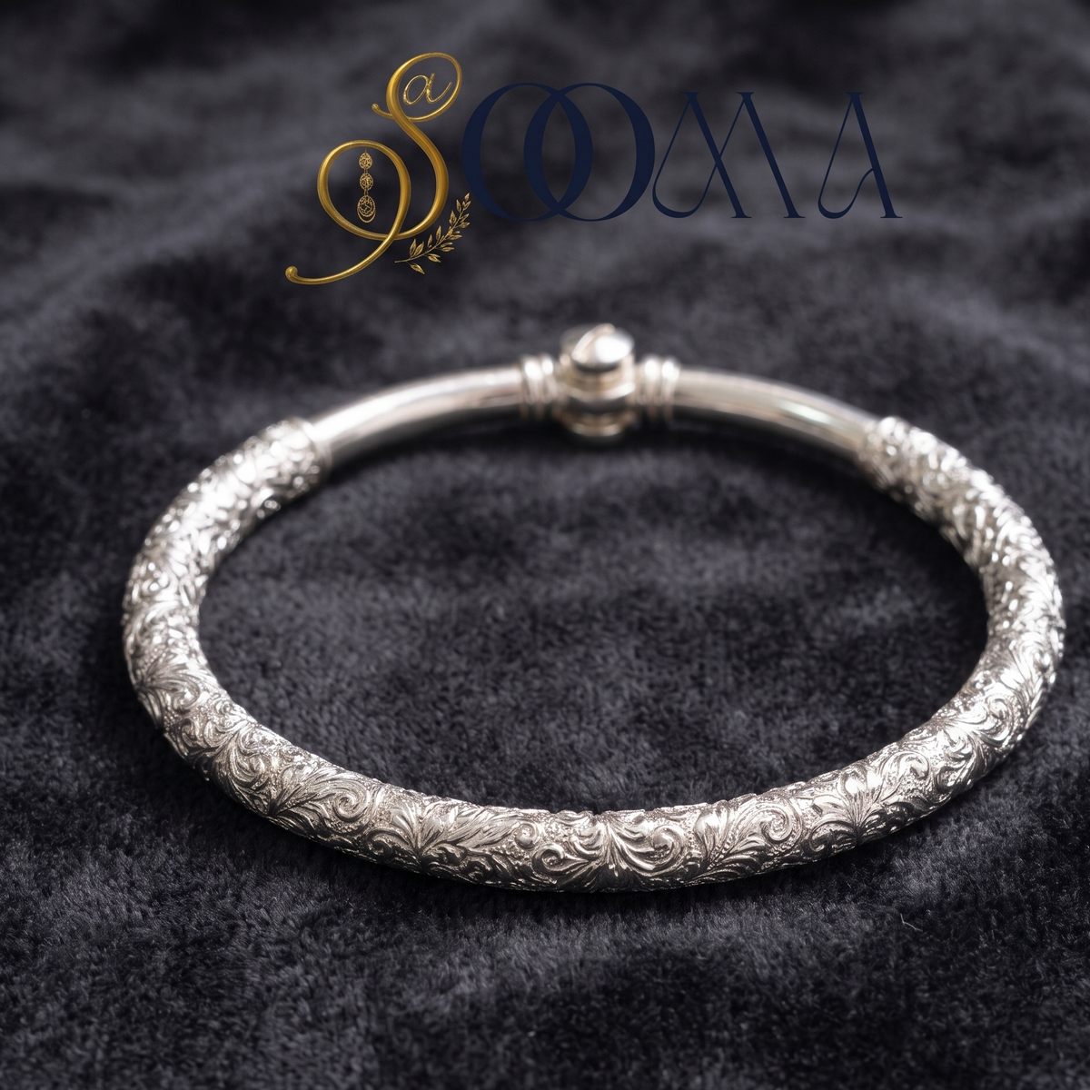 An ornate silver bangle bracelet with intricate floral engraving, displayed on a dark textured velvet background with the brand name 'SOOMA' at the top.