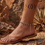 Model wearing adjustable black cord silver flower payal anklet with extension chain on warm stone background