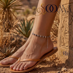 Side view of foot wearing oxidized silver floral bead black cord anklet paired with tan leather sandals outdoors