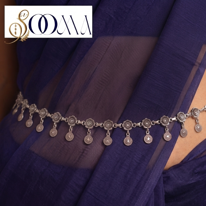 A silver-toned waist chain with ornate floral motifs and dangling coin charms, shown worn around the waist of a model draped in a deep purple fabric. The brand logo 'SOOMA' is visible in the top-left corner, and a '1 cm' size marker is at the bottom.