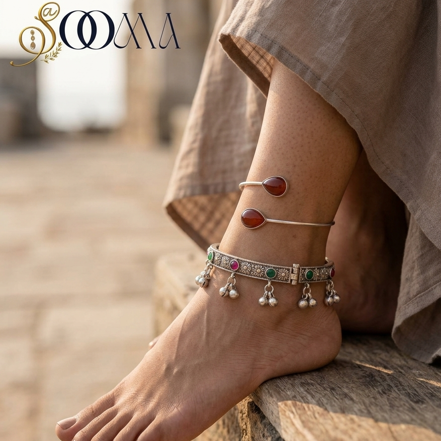 Side perspective view of model wearing royal floral ghungroo kada and carnelian bypass ankle cuff stack paired with beige linen skirt