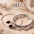 Sooma brand flat lay view of 2-piece ankle stack featuring a carnelian bypass cuff and ruby-emerald floral ghungroo kada on beige stone surface