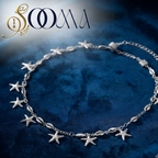 Sooma brand silver starfish and cowrie shell waist chain displayed flat on deep blue velvet background