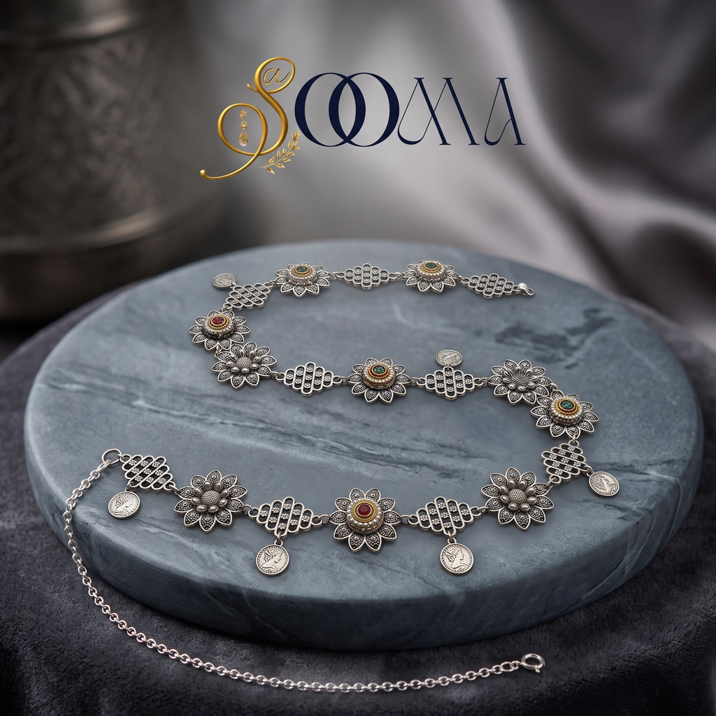 Front view of oxidized silver Sooma brand oxidized silver floral and coin charm waistbelt displayed coiled on grey marble disc