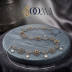 Front view of oxidized silver Sooma brand oxidized silver floral and coin charm waistbelt displayed coiled on grey marble disc