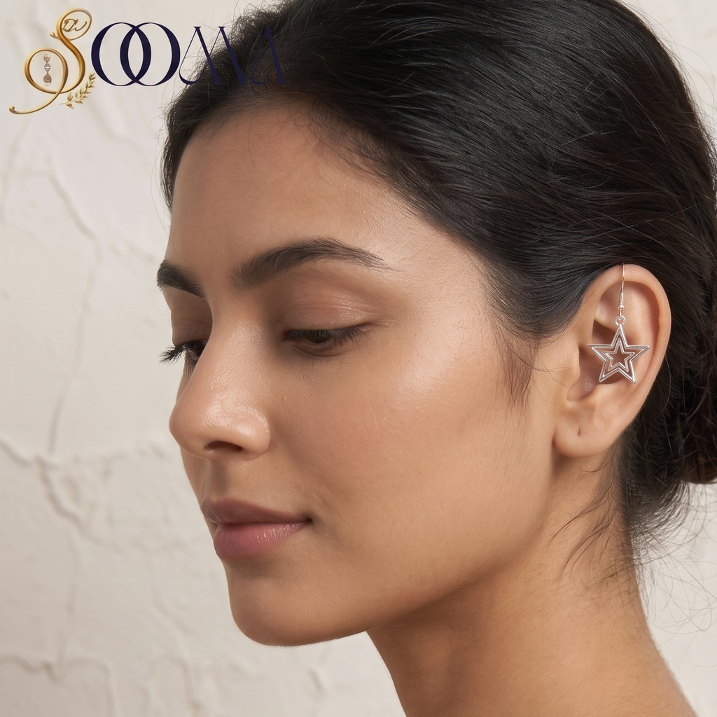 A woman in profile wearing a delicate silver star-shaped ear cuff earring, with her hair styled in a low bun against a textured beige wall. The brand logo 'SOOMA' is visible in the top left corner.