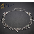 An ornate silver-toned belly chain necklace with intricate filigree, dangling star charms, and small amber-colored stone accents, displayed on a dark textured background with the SOOMA brand logo in the top left corner.