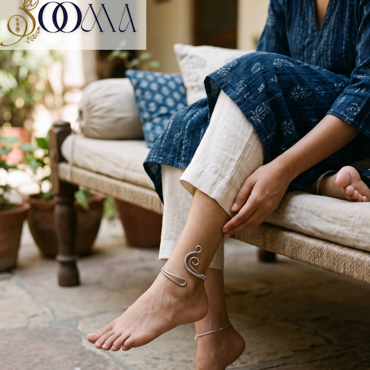 Full lifestyle portrait of model on woven charpoy showing the high-ankle fit of the wire-wrapped spiral wave silver cuff
