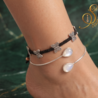Close-up view of model foot adorned with a bohemian black butterfly cord anklet and teardrop rainbow moonstone silver bypass cuff