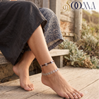 Close-up view of woman foot on wooden deck adorned with a 2-piece layered silver butterfly anklet set