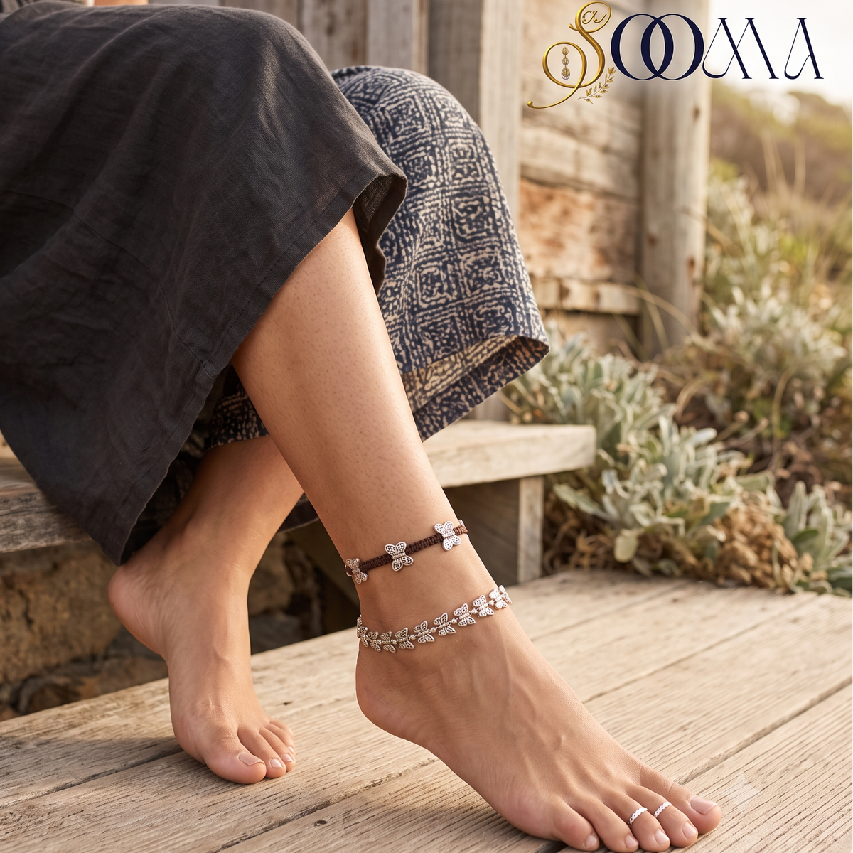 Close-up view of woman foot on wooden deck adorned with a 2-piece layered silver butterfly anklet set
